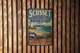 A vintage metal sign for Scusset Beach, Massachusetts, featuring a lighthouse and beach scene.