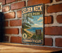 A vintage metal sign for Selden Neck State Park in Connecticut, featuring a scenic beach landscape with pine trees and a blue sky with clouds.