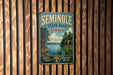 A vintage metal sign for Seminole State Park in Georgia, featuring a scenic landscape with a lake and trees.