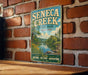 A vintage metal sign for Seneca Creek State Park in Maryland, featuring a scenic illustration of the park's natural and historical attractions.