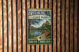A vintage-style metal sign for Sesquicentennial State Park in South Carolina, featuring a scenic landscape with a bridge and trees.