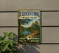 A vintage-style sign for Sesquicentennial State Park in South Carolina, featuring a scenic image of a wooden bridge and a lake surrounded by trees.