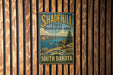 A vintage metal sign for the Shadehill State Recreation Area in South Dakota, featuring a scenic landscape with a lake and mountains.
