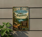 A metal sign on a wall advertising Shawme-Crowell State Forest in Massachusetts, featuring a scenic image of pine forests and a lake.