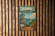 A vintage-style metal sign for Shawnee State Park, Ohio, featuring a scenic landscape with a river, mountains, and a pine tree.