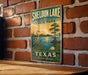 A vintage-style sign for Sheldon Lake State Park in Texas, featuring a scenic illustration of a lake, a bird, and a palm tree.