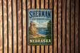 A vintage-style metal sign for Sherman State Recreation Area in Nebraska, featuring a scenic landscape with a rocky outcrop, a lake, and a sailboat.