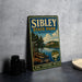 A vintage metal sign for Sibley State Park in Minnesota, featuring a scenic landscape with pine trees, a lake, and mountains.