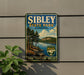 A vintage-style sign for Sibley State Park in Minnesota, featuring a scenic landscape with pine trees, a lake, and mountains.