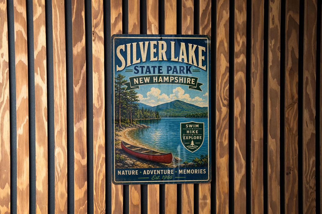 A vintage-style metal sign for Silver Lake State Park in New Hampshire, featuring a scenic image of a lake, mountains, and a canoe.