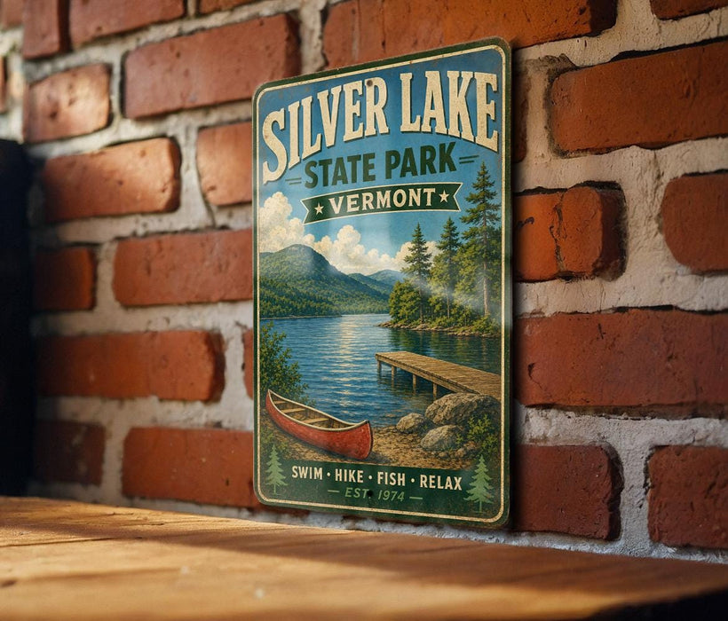 A vintage-style metal sign for Silver Lake State Park in Vermont, featuring a scenic image of a lake, mountains, and a red canoe.