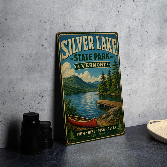 A vintage-style metal sign for Silver Lake State Park in Vermont, featuring a scenic image of a lake, mountains, and a canoe.