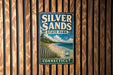 A vintage metal sign for Silver Sands State Park in Connecticut, featuring a scenic beach landscape with a lighthouse and a bird in flight.