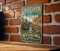 A vintage-style metal sign for Sinks Canyon State Park in Wyoming, featuring a scenic illustration of the canyon landscape.