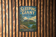 A vintage-style metal sign for Sleeping Giant State Park in Connecticut, featuring a scenic landscape with a mountain and lake.