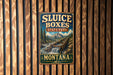 A vintage-style sign for Sluice Boxes State Park in Montana, featuring a scenic mountain landscape with a waterfall.