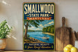 A vintage-style metal sign for Smallwood State Park, Maryland, featuring a scenic image of a lake and a boat, with the text "Smallwood State Park, Maryland, Natural Beauty, Year Round Adventure" displayed prominently.
