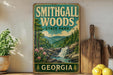 A vintage-style metal sign for Smithgall Woods State Park in Georgia, featuring a scenic landscape with a waterfall and pine trees.