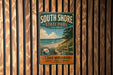 A vintage metal sign for South Shore State Park in Illinois, featuring a scenic beach landscape with a wooden fence and a bird in flight.
