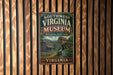 A vintage metal sign for the Southwest Virginia Museum, featuring a historical illustration of a log cabin and a watermill, mounted on a wooden wall.