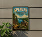 A vintage metal sign for Spencer State Forest in Massachusetts, featuring a scenic landscape with pine trees, a lake, and a trail.