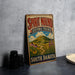 A vintage-style metal sign for Spirit Mound Historic Prairie in South Dakota, featuring a scenic landscape with a mountain, flowers, and a winding path.