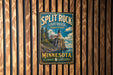 A vintage metal sign for Split Rock Lighthouse State Park in Minnesota, featuring a lighthouse on a cliff overlooking a lake.