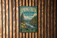 A vintage-style metal sign for Spring Creek State Park in Washington, featuring a scenic landscape with a river, mountains, and pine trees.