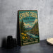 A vintage-style sign for Spring Creek State Park in Washington, featuring a scenic landscape with a river, mountains, and pine trees.