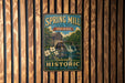 A vintage-style metal sign for Spring Mill State Park, Indiana, featuring a scenic illustration of a waterfall and a mill.