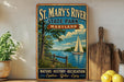 A vintage-style metal sign for St. Mary's River State Park in Maryland, featuring a scenic image of a sailboat on the river.