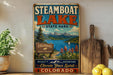 A vintage-style metal sign for Steamboat Lake State Park, featuring a scenic landscape with mountains, a lake, and a sign for the park's wildlife and parks and wildlife facilities.