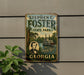 A vintage-style metal sign for Stephen C. Foster State Park in Georgia, featuring a portrait of a man and a depiction of the Savannah River.
