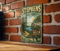 A vintage-style metal sign for Stephens State Forest in Iowa, featuring a scenic landscape with a river and trees.