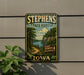 A vintage-style metal sign for Stephens State Forest in Iowa, featuring a scenic landscape with a river, trees, and mountains.