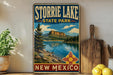 A vintage-style sign for Storrie Lake State Park in New Mexico, featuring a scenic landscape with a lake, mountains, and pine trees.