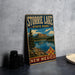 A vintage metal sign for Storrie Lake State Park in New Mexico, featuring a scenic landscape with a lake, mountains, and a mesa.