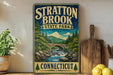 A vintage-style sign for Stratton Brook State Park in Connecticut, featuring a scenic illustration of a river, bridge, and forest.