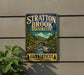 A vintage-style metal sign for Stratton Brook State Park in Connecticut, featuring a scenic landscape with a bridge and waterfall.