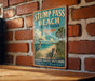A vintage-style metal sign for Stump Pass Beach, Florida, featuring a beach scene with a crane and palm trees.