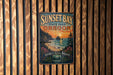 A vintage metal sign for Sunset Bay State Park in Oregon, featuring a scenic landscape with a sunset over the ocean and mountains.