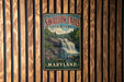 A vintage-style metal sign for Swallow Falls State Park in Maryland, featuring a waterfall and lush greenery.