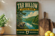 A vintage-style sign for Tar Hollow State Park, featuring a scenic landscape with a river and forest, is displayed on a wooden shelf next to a wooden cutting board and some lemons.