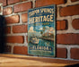 A vintage-style metal sign for Tarpon Springs Heritage State Park in Florida, featuring a boat on a river and a coastal scene.