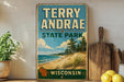 A vintage-style sign for Terry Andrea State Park in Wisconsin, featuring a scenic beach landscape with pine trees and a lake.
