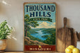 A vintage-style sign for Thousand Hills State Park in Missouri, featuring a scenic landscape with a lake and mountains.