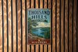 A vintage metal sign for Thousand Hills State Park in Missouri, featuring a scenic landscape with a lake and mountains.