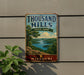 A vintage-style sign for Thousand Hills State Park in Missouri, featuring a scenic landscape with a lake and mountains.