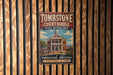 A vintage-style metal sign for Tombstone Courthouse, a historic park in Arizona, with a wooden fence in the background.