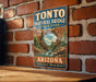 A vintage-style metal sign for Tonto Natural Bridge State Park in Arizona, featuring a scenic illustration of the park's natural landscape.